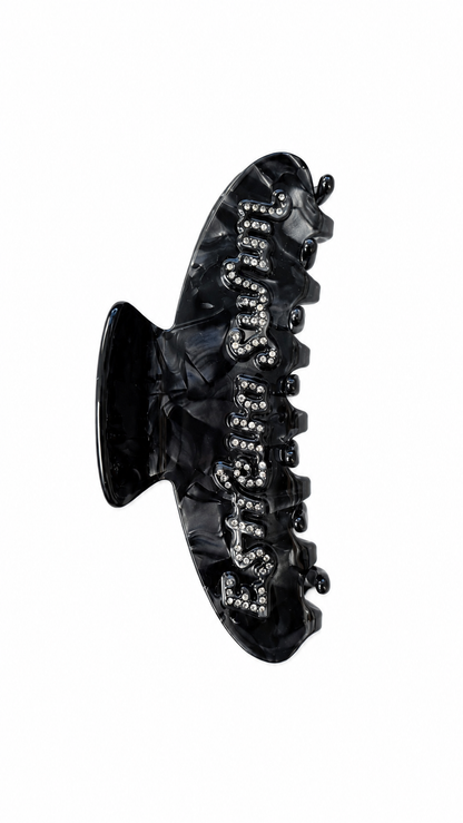 Estrella Swim black hair claw clip with rhinestone logo on white background.